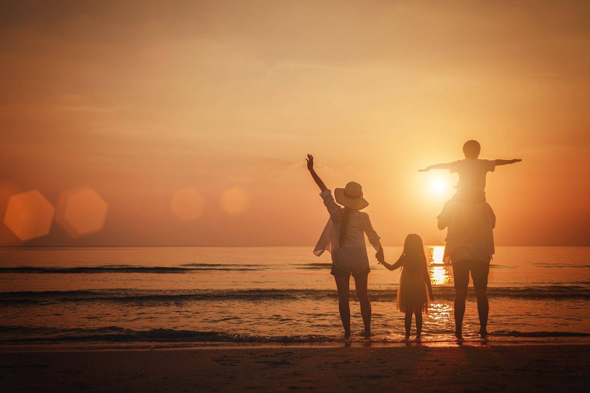 A family spends time together on the beach at sunset.